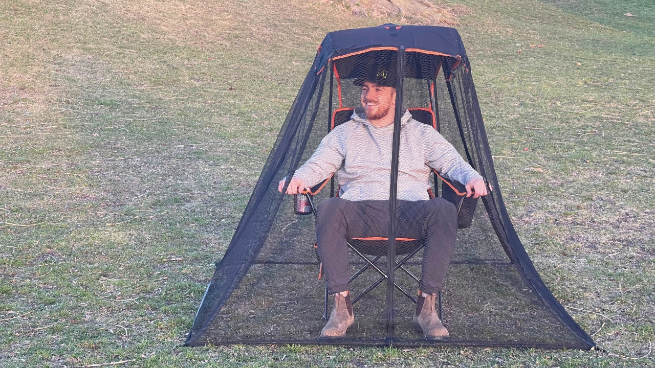 Man enjoying a bug-free outdoor experience as he sits in a park, comfortably within his Bug Beater Outdoor Chair.